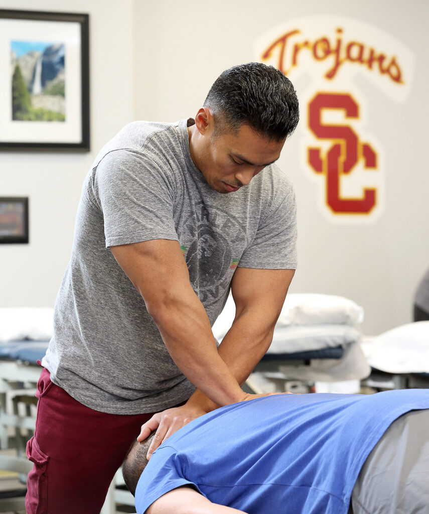 Physical therapist pressing down on a patient's spine