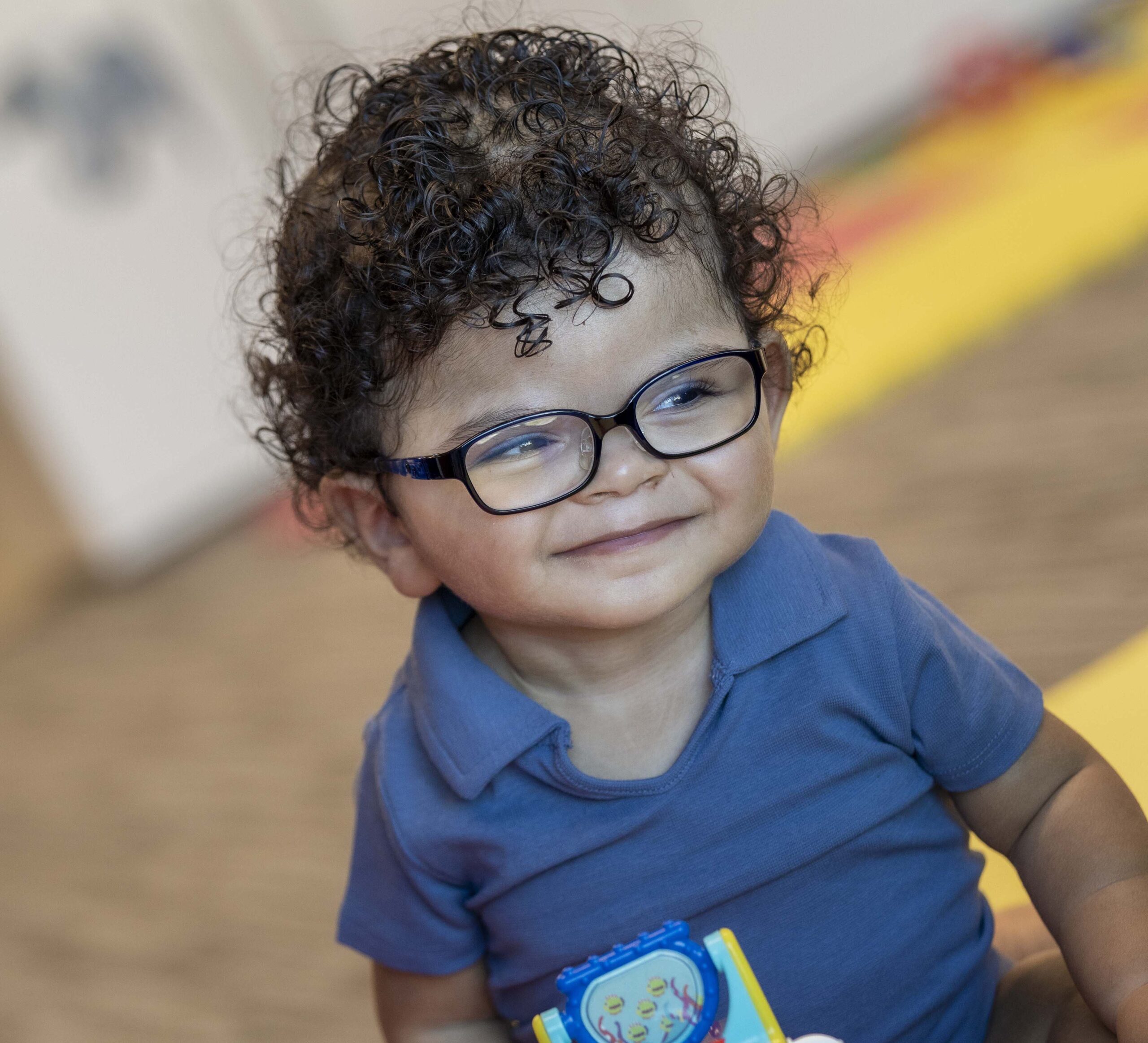 Infant with black curly hair and eyeglasses