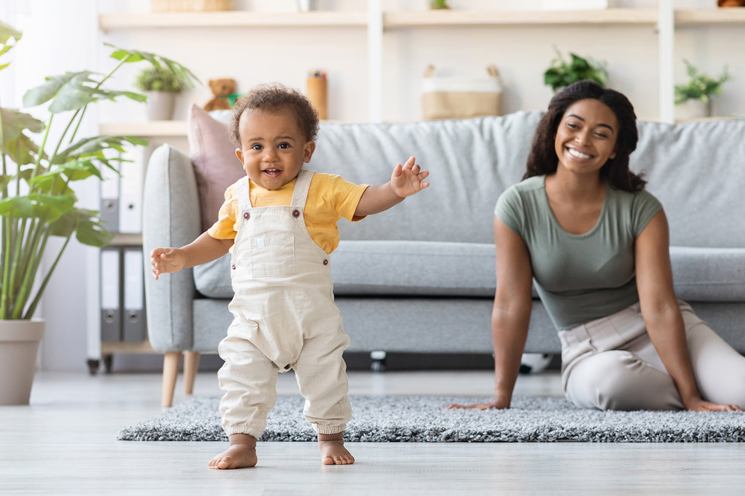 Infant with mom, learning to walk
